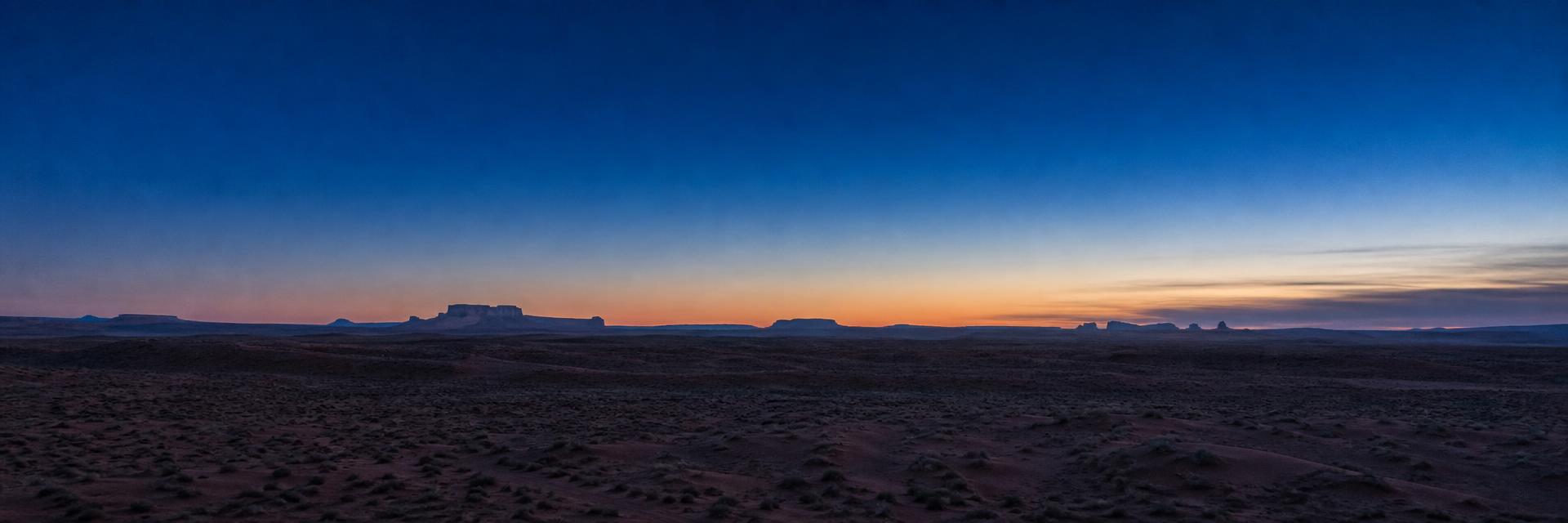 Wide desert horizon at blue hour with distant mesas under an indigo sky