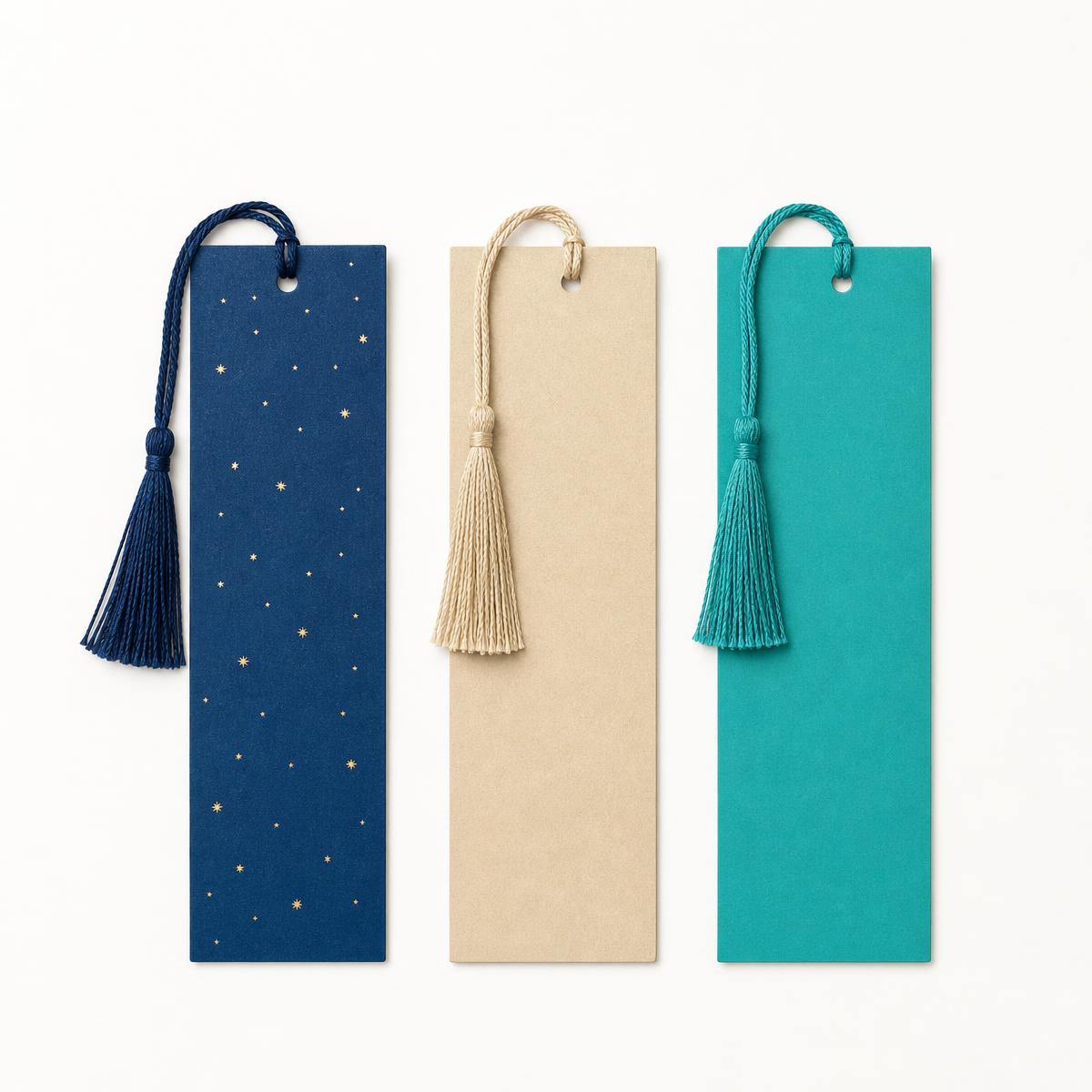 Three tasseled bookmarks in indigo, sand and turquoise laid flat on a studio background