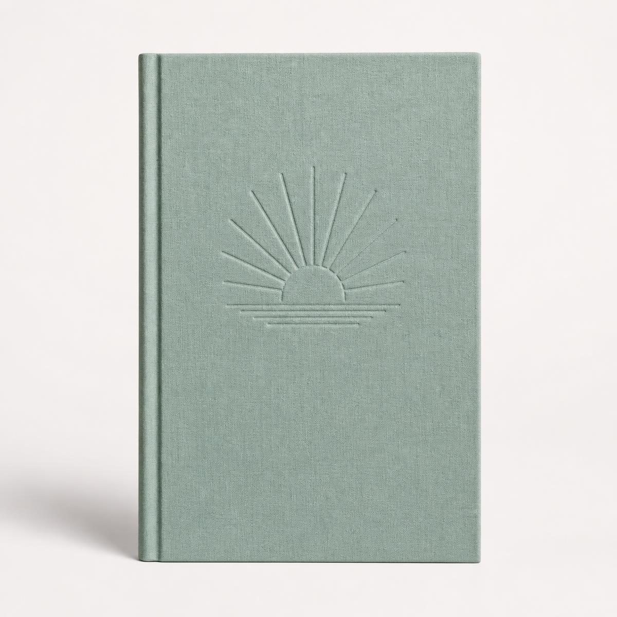 Sage green softcover book standing upright against a clean studio background